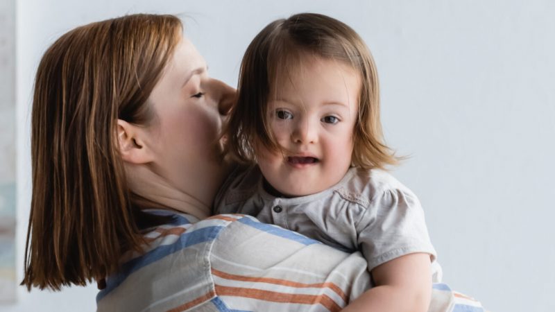 Photo of a mum holding a smiling baby over her shoulder